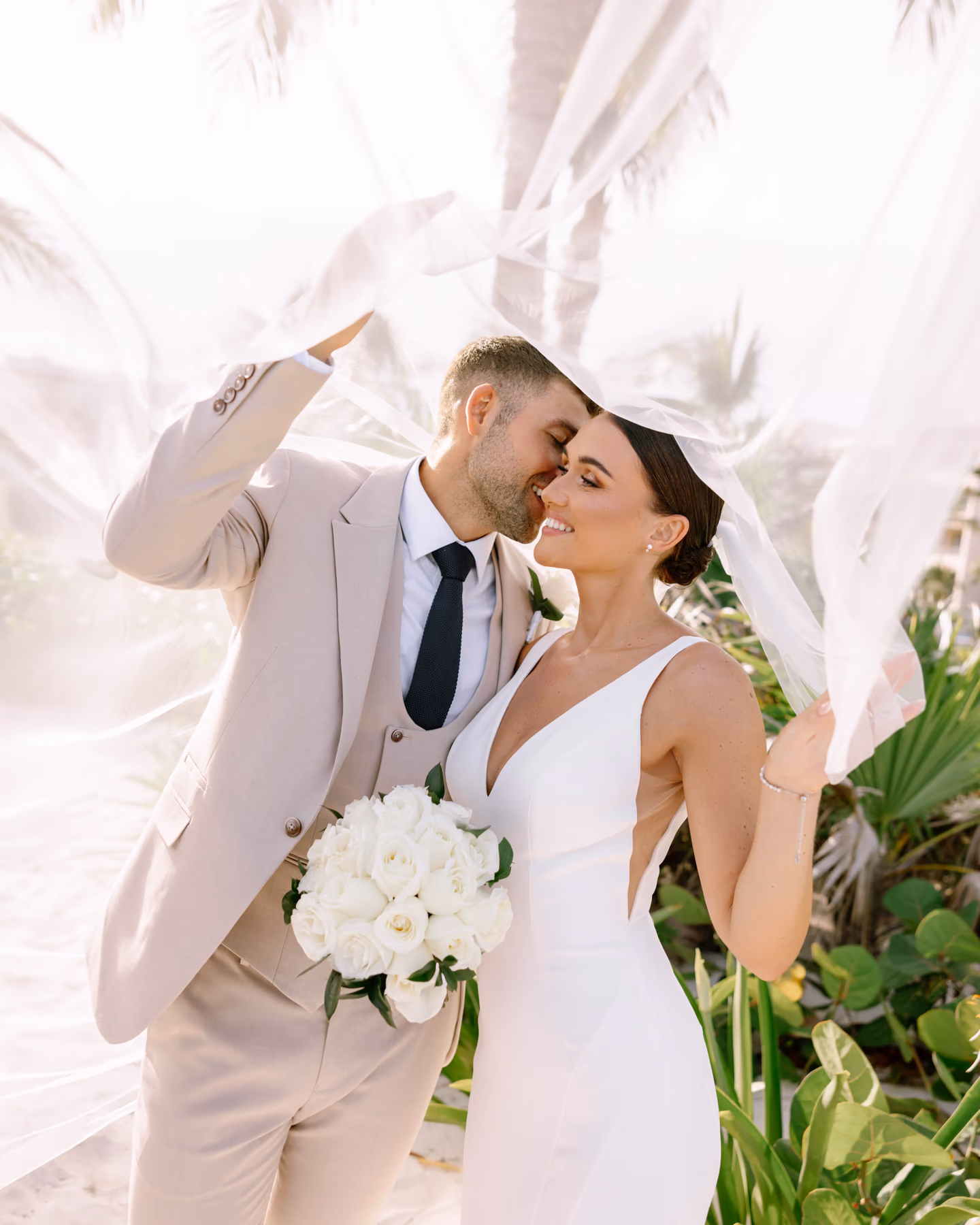 A couple laughing under a veil caught by the wind