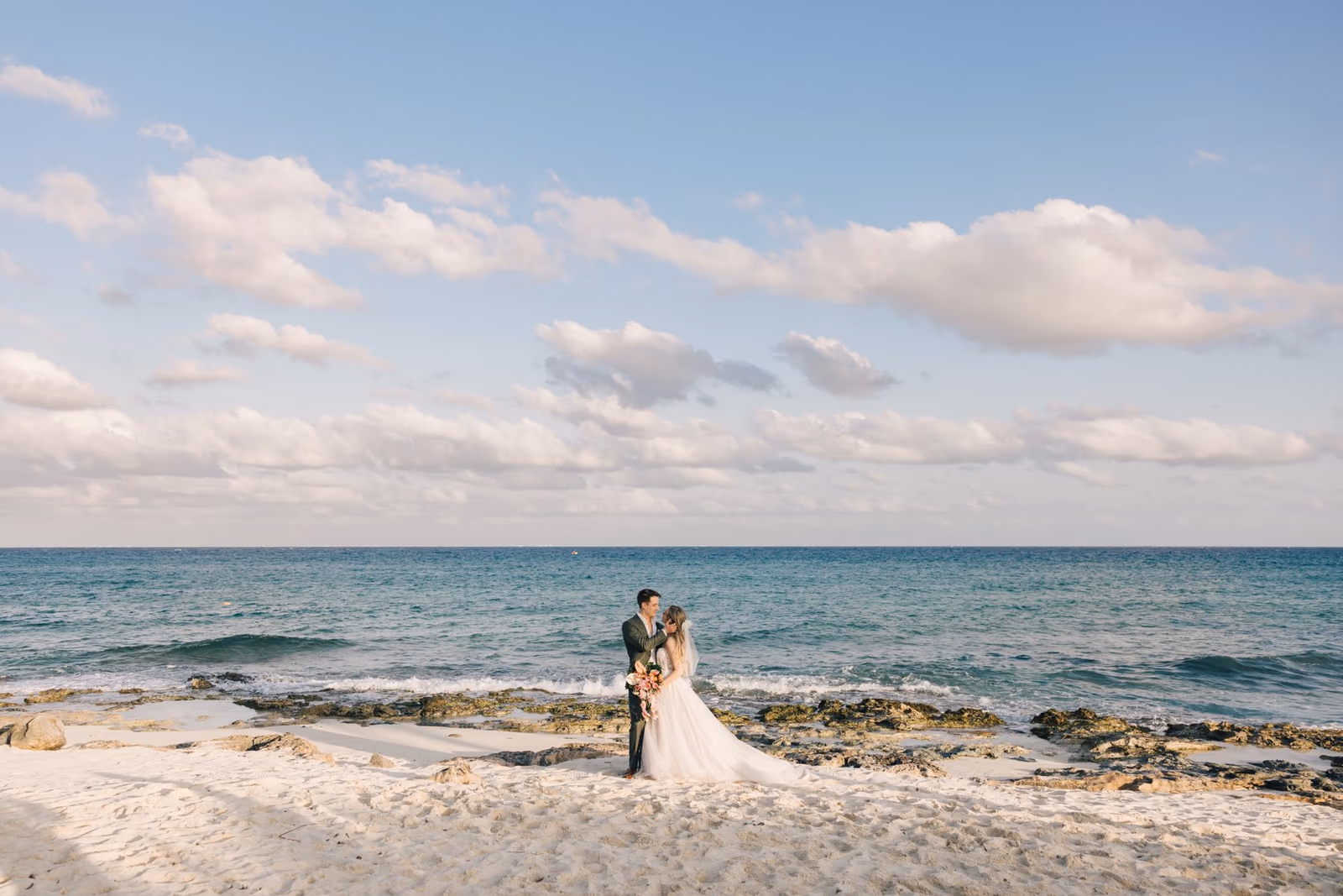 Couple kissing in front of the sea at their beach wedding at Hotel Xcaret Mexico by Diptych Studio