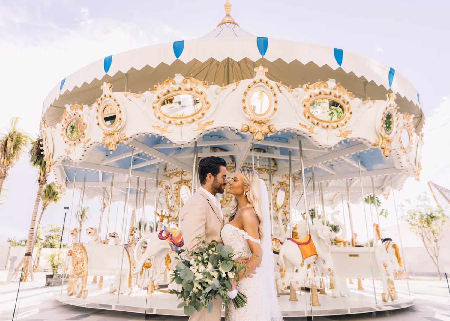 Bride and groom sharing a kiss in front of a carousel at Garza Blanca Cancun wedding.