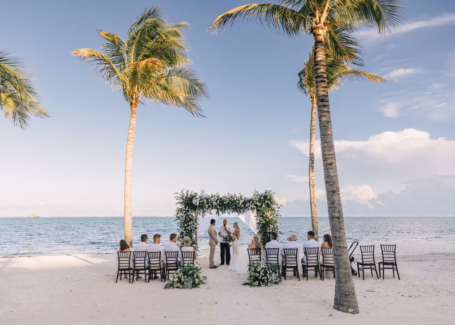 Bride and groom stand under the arch during their wedding ceremony at Garza Blanca Cancun