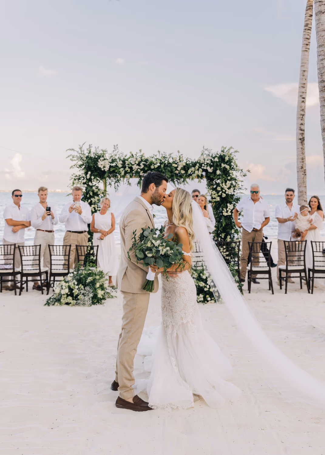 Newlyweds share a romantic kiss under the arch at Garza Blanca Cancun after their wedding ceremony